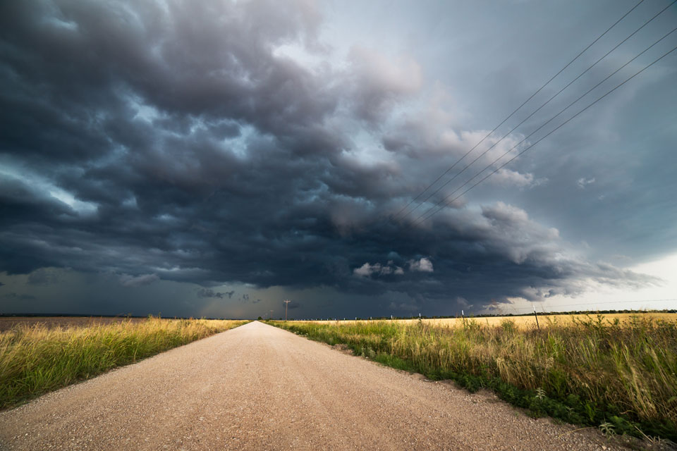 A dirt road with bad weather on the horizon