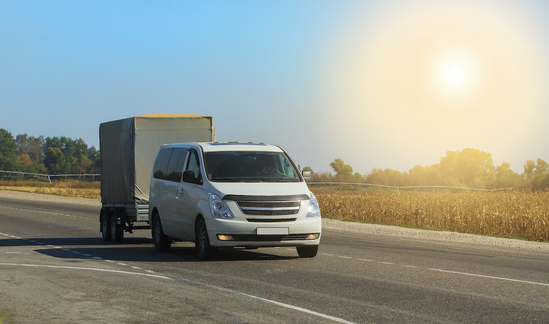 A van towing a trailer with a canopy on the back.