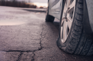 A parked car with a flat tyre on the side of the road. 