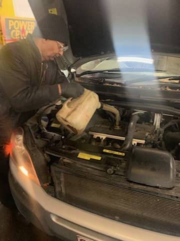 A man pouring fluid into a vehicle.