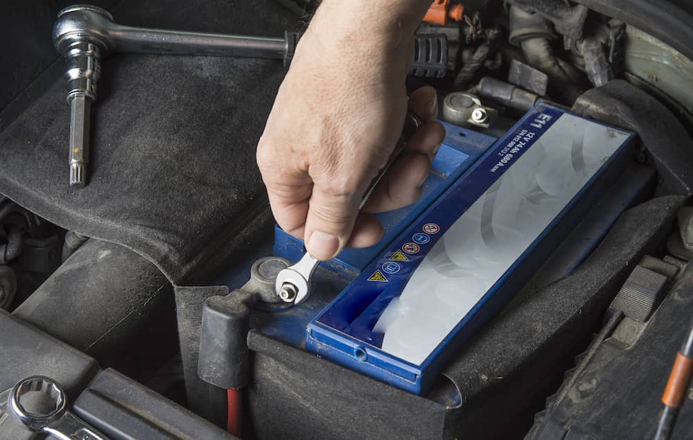 Using a shifter to loosen bolts on a car battery.