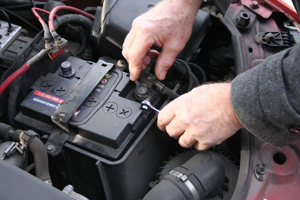 Loosening the battery terminal on a car battery.