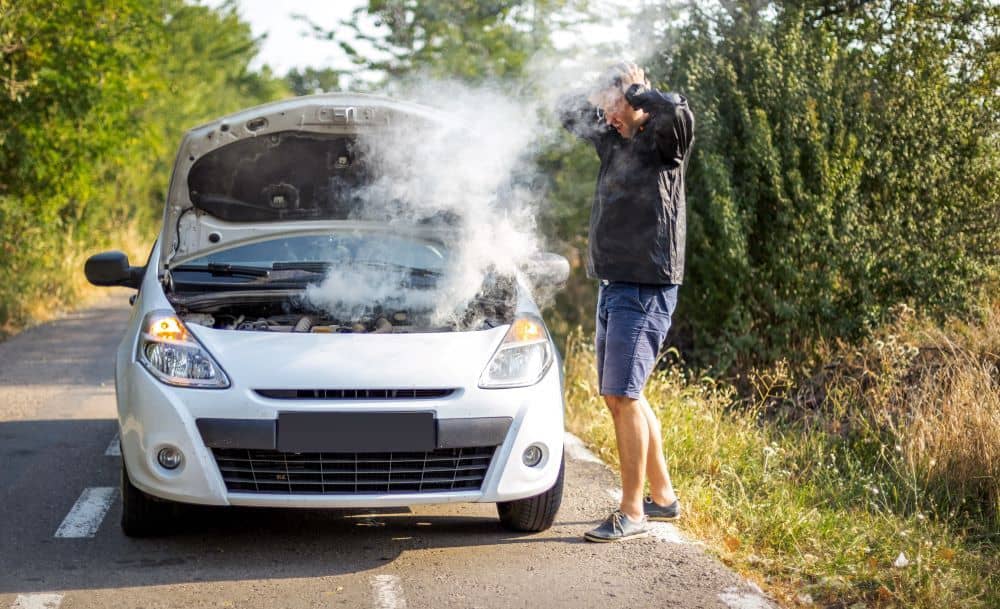 Man checking looking at smoking car engine. 