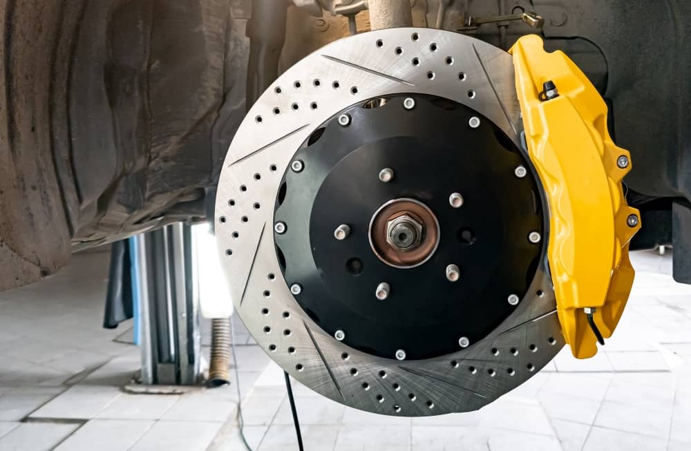 Car braking system - disc, pads, yellow hub and cooling holes.