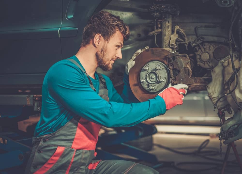 Mechanic checking car brake system in a workshop.