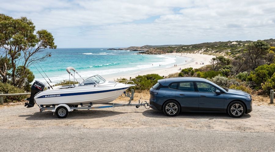 Electric vehicle towing a boat trailer near a Melbourne beach showing EV towing performance in Australia